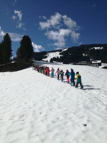 eine Gruppe von Menschen, die mit Skiern einen schneebedeckten Hang hinunterfahren