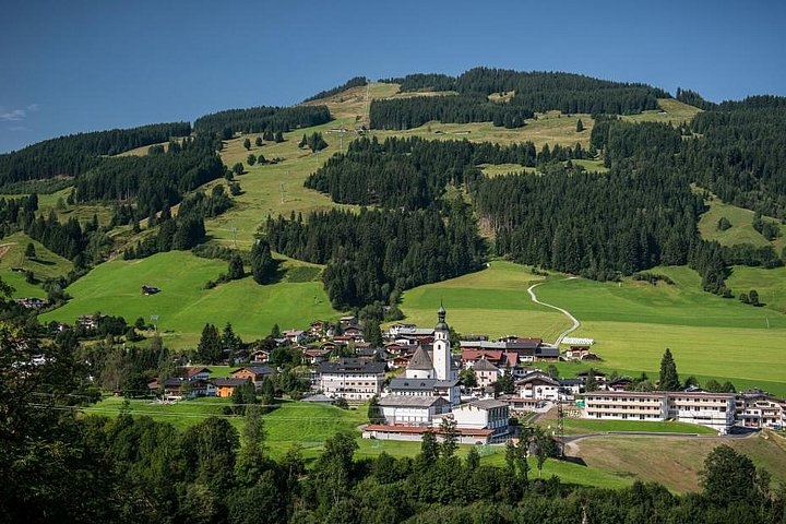ein Uhrturm auf einem saftig grünen Hang mit Schwarzwald im Hintergrund