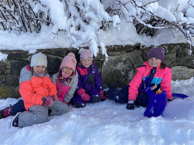 eine Gruppe kleiner Kinder, die neben einem Schneehaufen sitzen