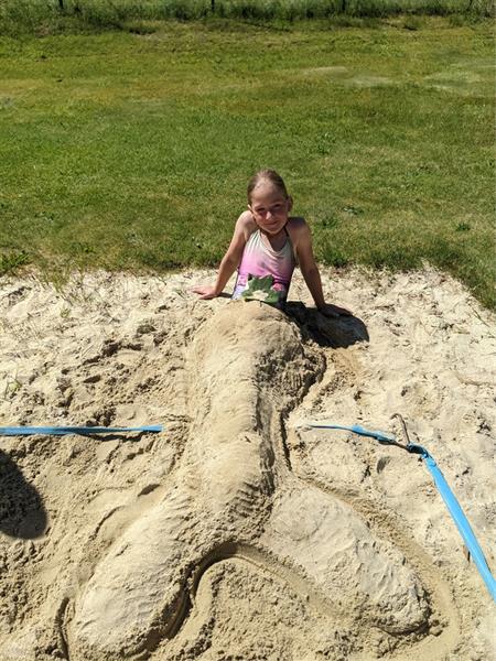 ein kleines Mädchen, das im Sand steht