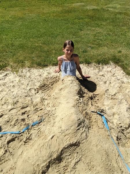 ein Mädchen, das im Sand sitzt